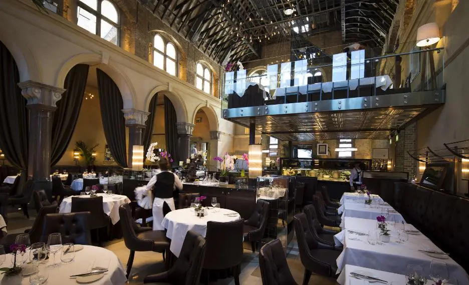 Restaurant dining room set with white linen beneath a vaulted ceiling