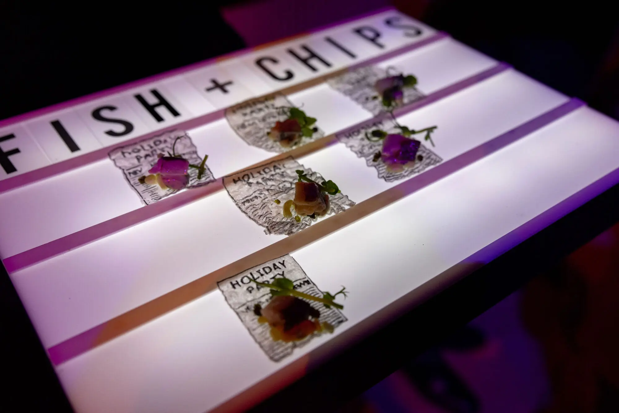Fish and chips canapé station with a backlit sign