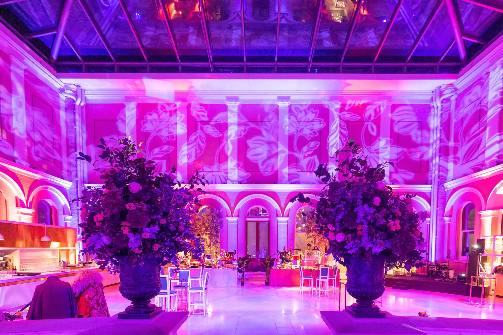 Ornate hall with tall floral displays lit in pink