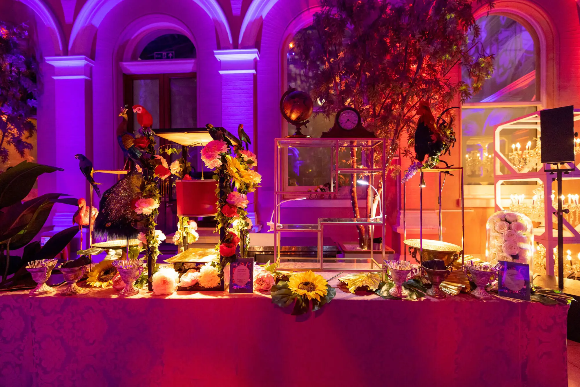 Styled bar with floral displays and lamps at an evening event