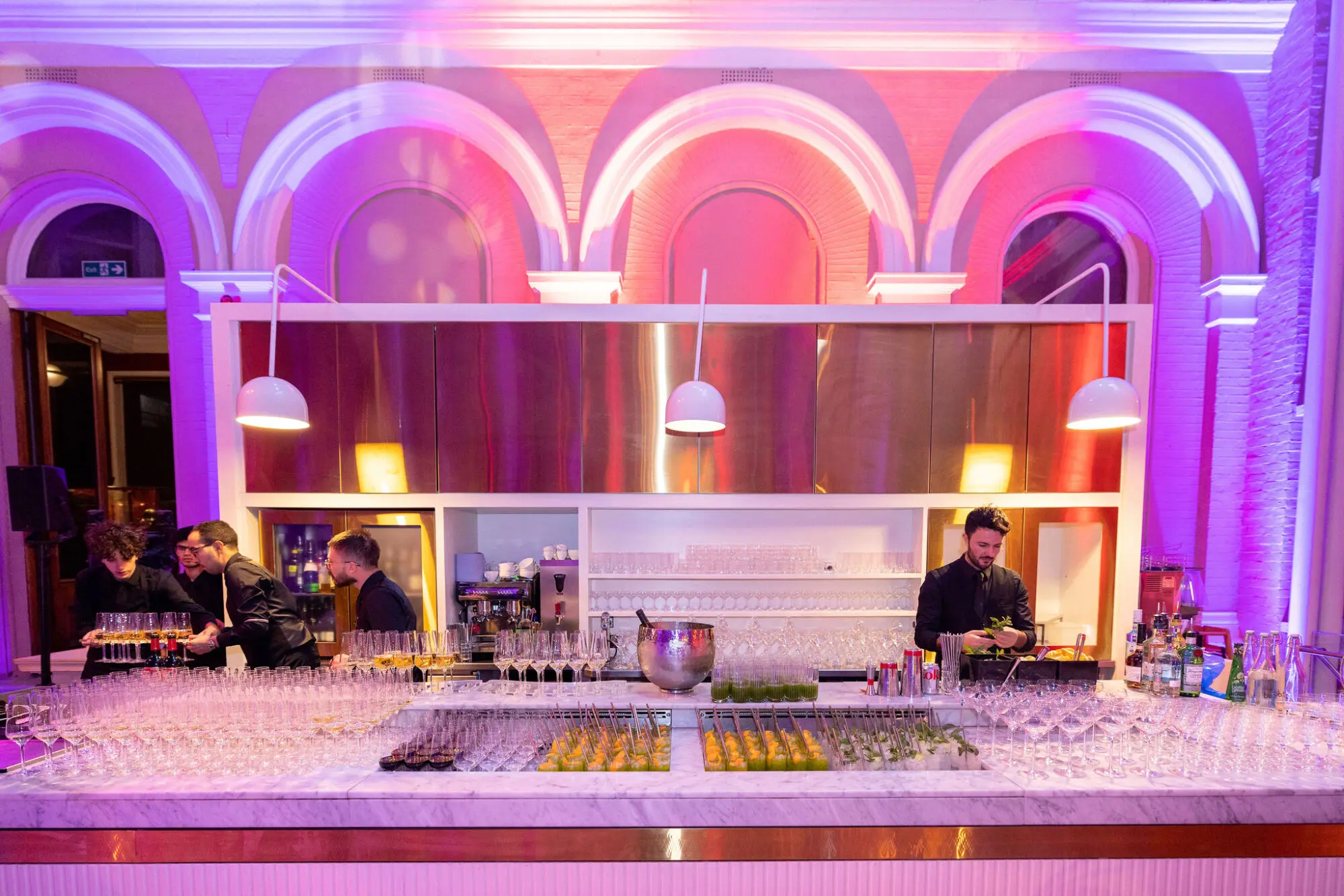 Long bar beneath arches lit in pink