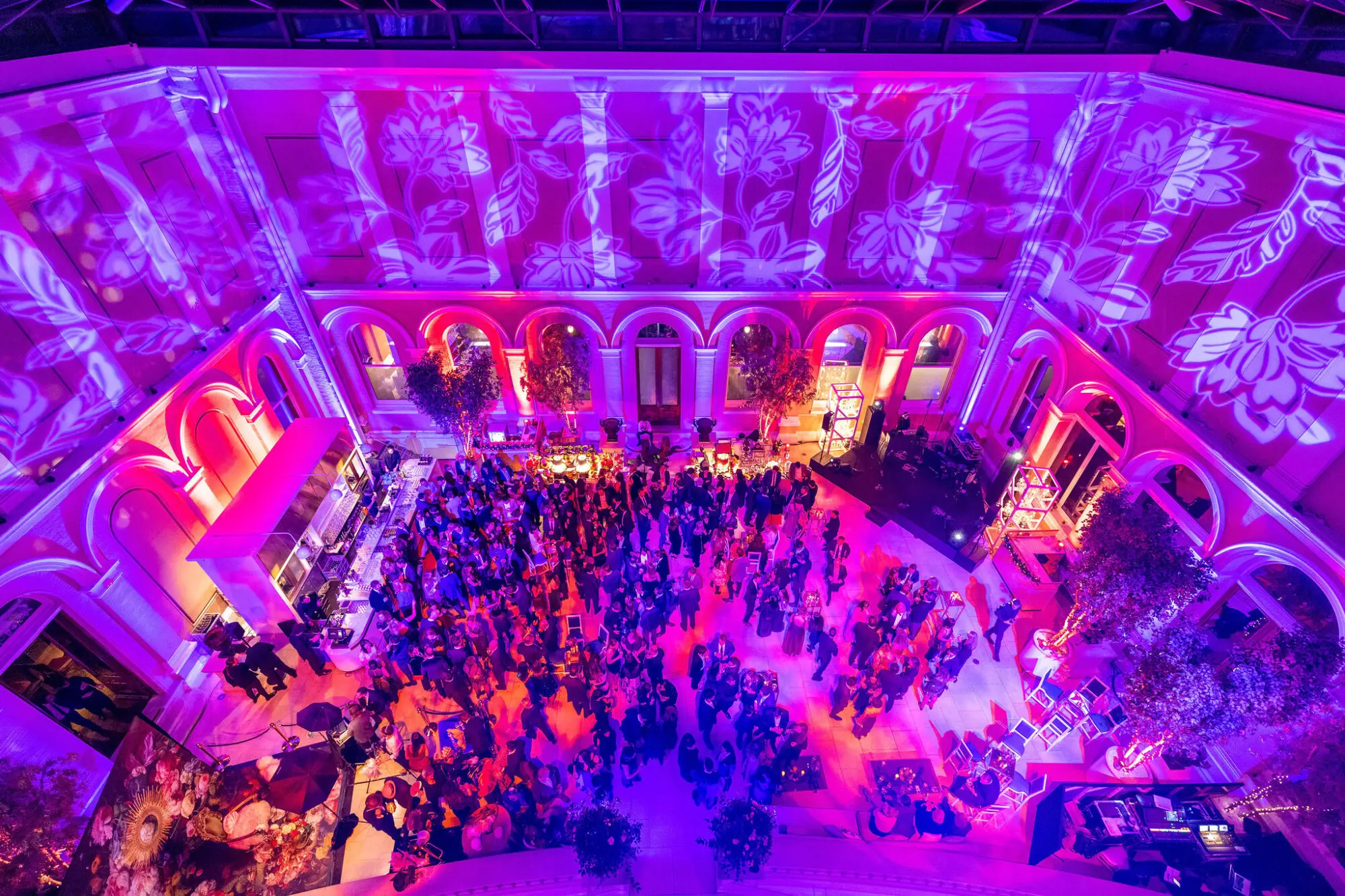 Guests filling an ornate hall lit in purple