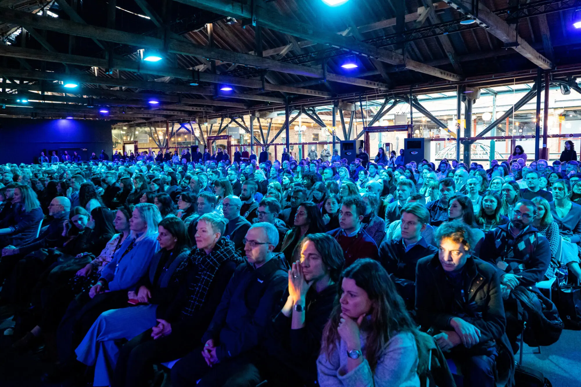 Delegates seated in a large auditorium lit in blue