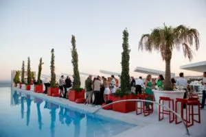 Poolside drinks reception with red furniture and palms