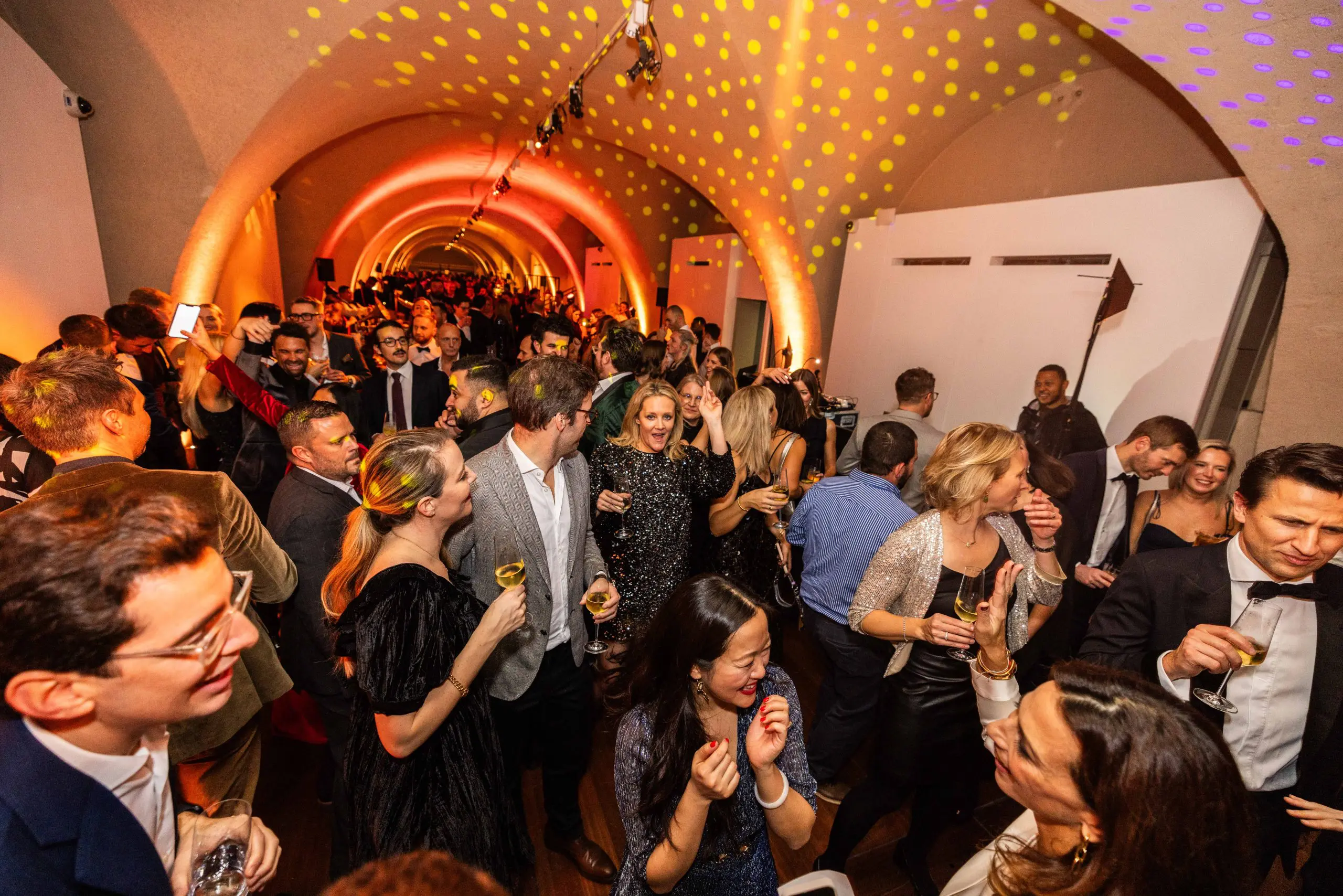 Guests at a drinks reception in a vaulted brick venue
